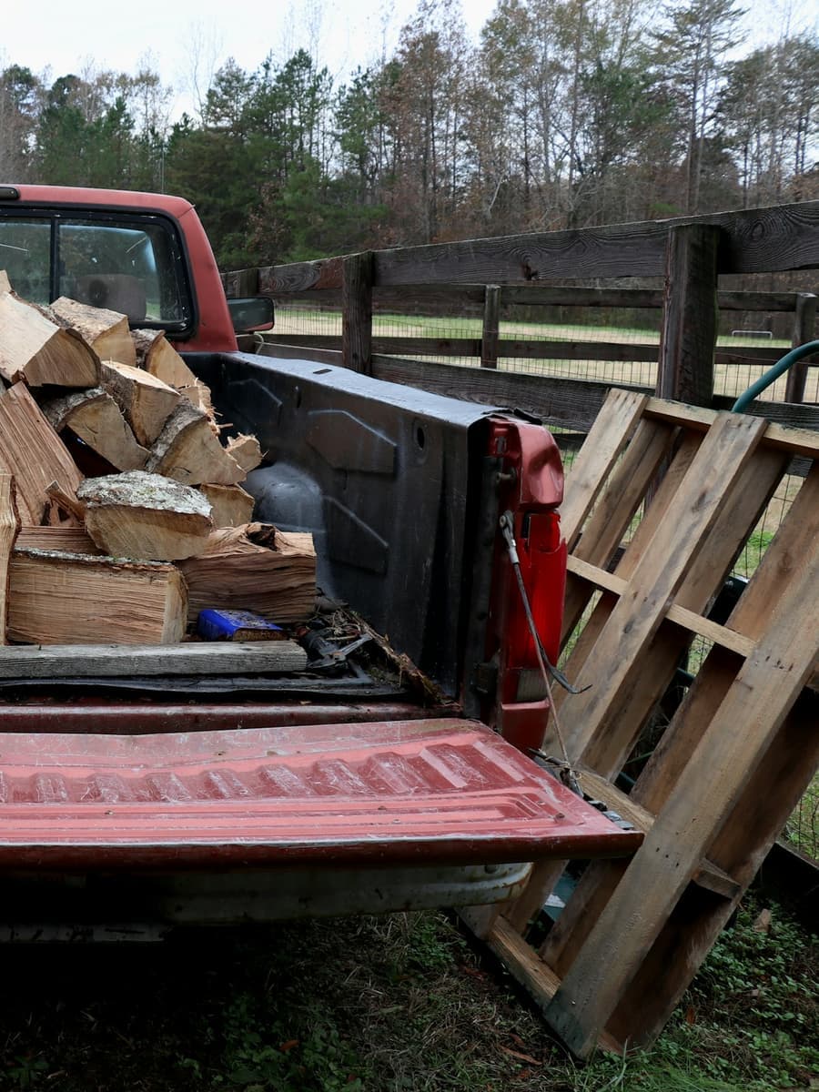 A pickup truck bed loaded with split firewood